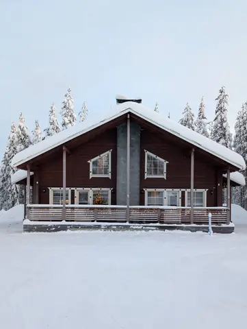 Chalet Nulkka cabin front with snow-covered pines in Levi